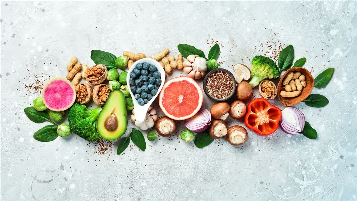 Avocado, citrus, nuts and greens laid out on a pale table