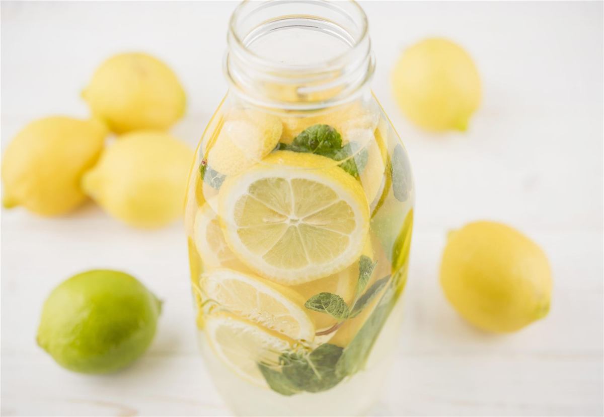 Lemons, a lime and a jar of lemon water with mint