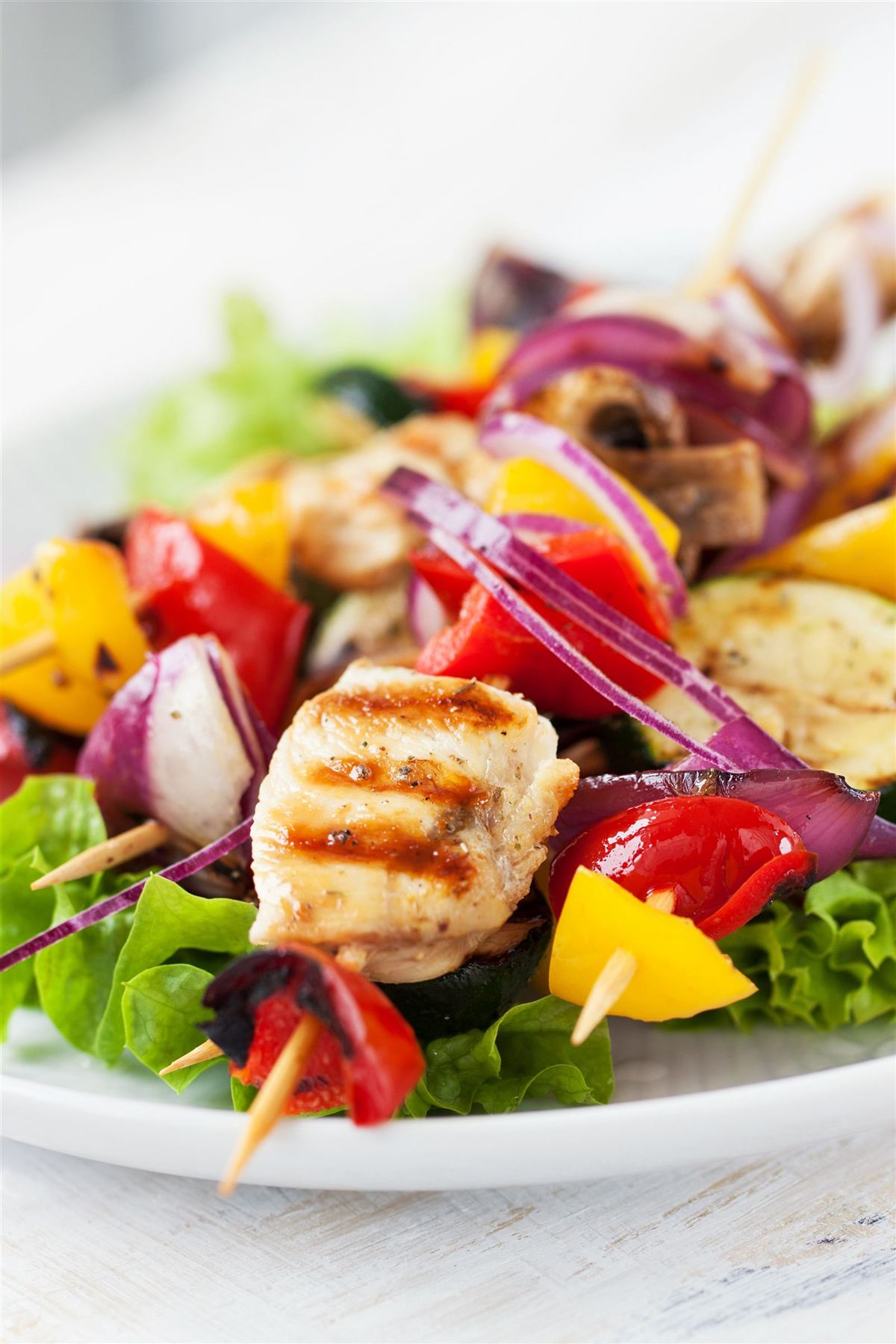 Grilled chicken and pepper skewers on salad